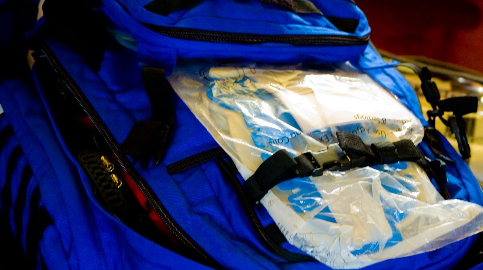 A blue backpack with a plastic bag in it.