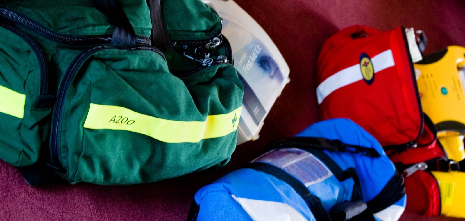 A group of first aid bags are lined up on a floor.